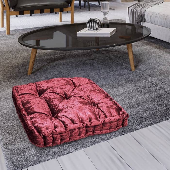a crushed red velvet floor pillow on the floor in a living room