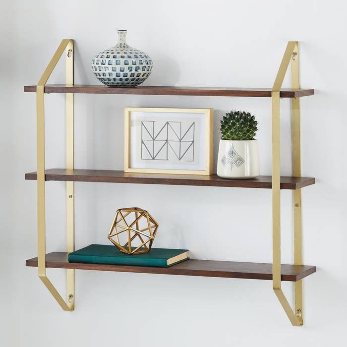 three wooden shelves with gold harware hanging on a wall