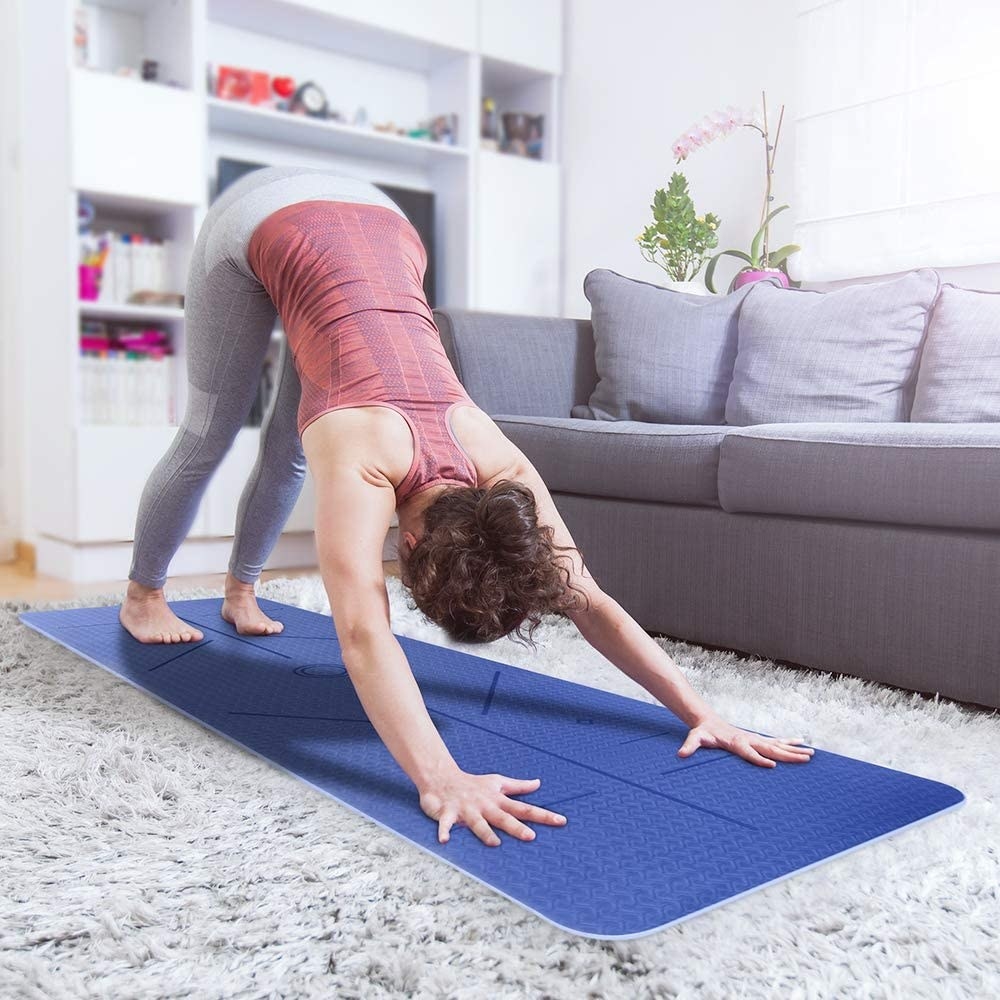 A person stretching on their yoga mat in a living room 