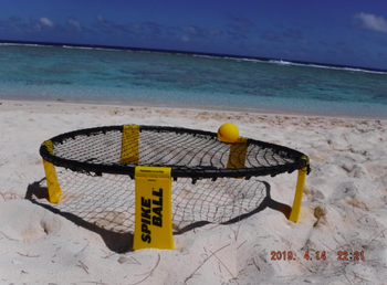 Round elevated net with ball in center placed in sand on beach 