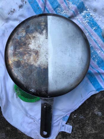 A reviewer's photo of a stainless steel pan that is tarnished on one side and clean on the other after being treated with the formula
