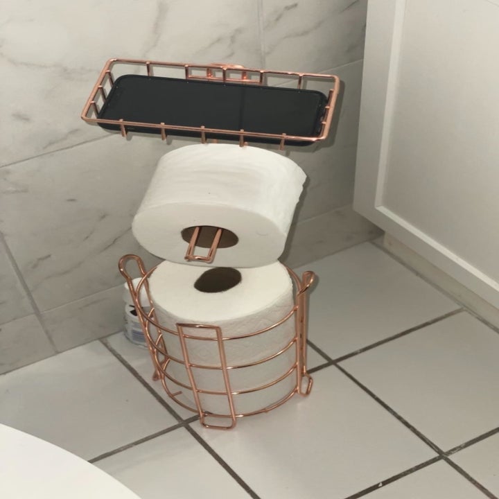 reviewer photo showing the toilet paper stand in their bathroom with phone on top in the holder