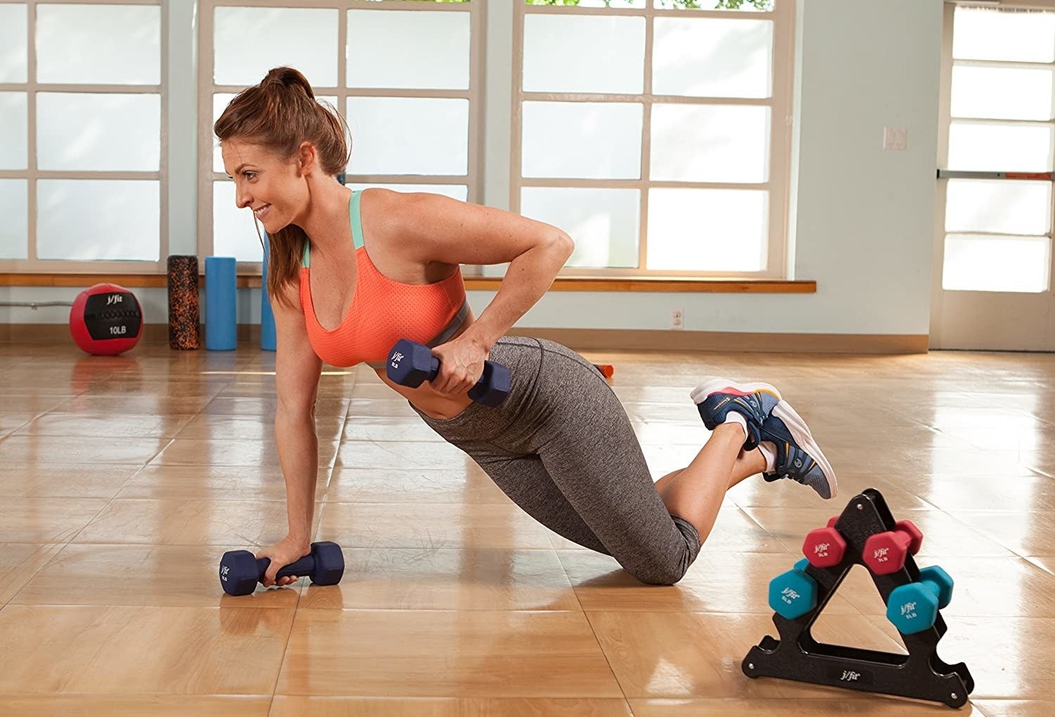A person using the eight pound weights in a pushup position, next to the triangular rack where the other two pairs are stored