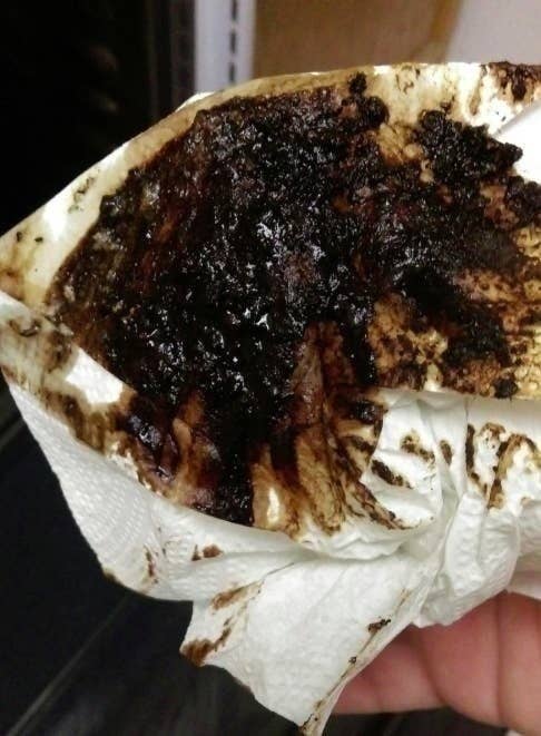 A reviewer photo of a paper towel that wiped up the oven after using the spray completely dirty from the amount of gunk it picked up