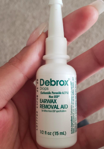 A reviewer holding the Debrox earwax removal drops