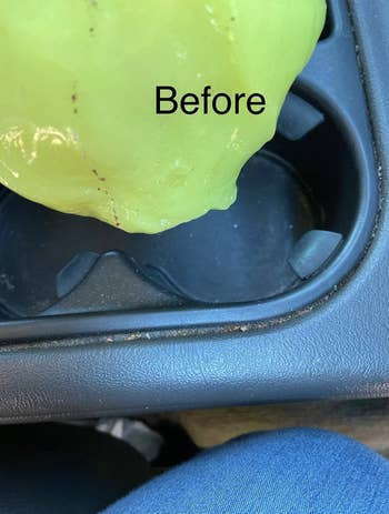 A yellow squishy putty hovering above a car drink holder with crumbs in it 