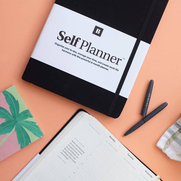 A small planner on a plain background with a pen next to it