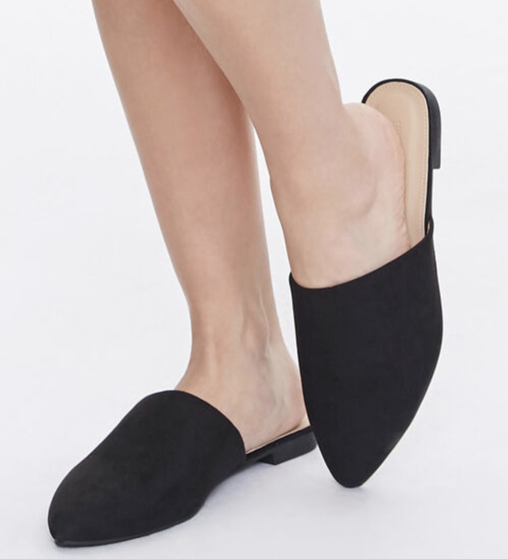 Model is wearing black pointed mules