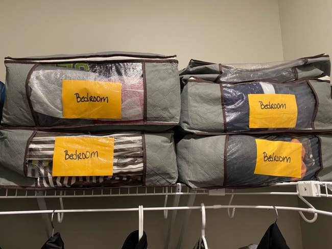 reviewer photo showing foldable storage bags filled with clothing and labeled on top shelf of their closet 