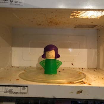 A reviewer's before photo which shows their dirty microwave and the cleaner sitting inside