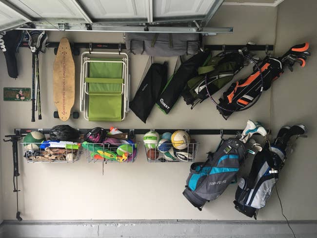 reviewer photo showing their garage completely organized with everything on their wall hanging from the track rails, including beach chairs, golf clubs, kids' toys, etc. 
