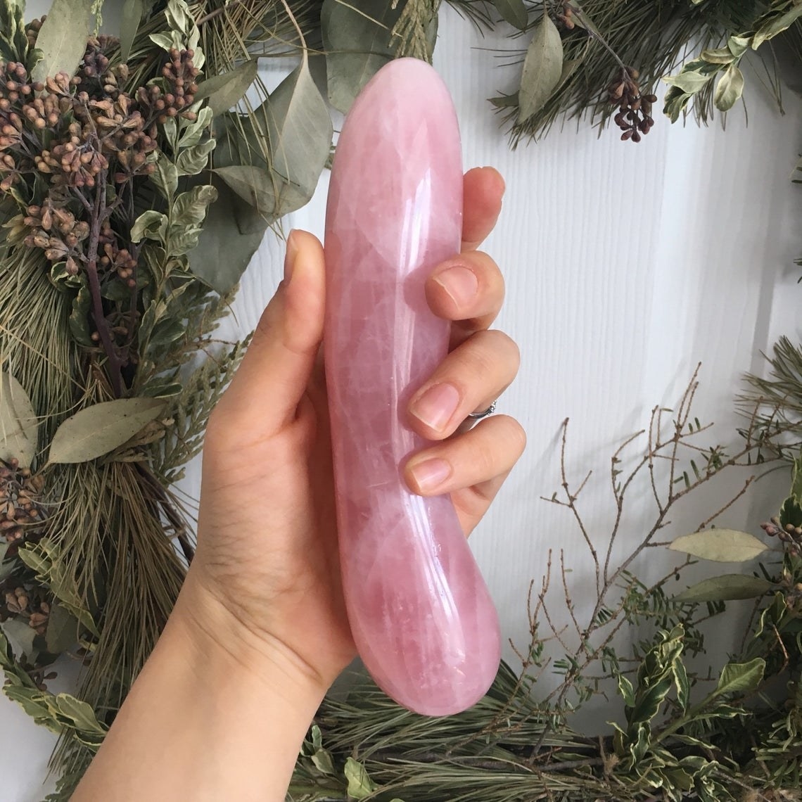hand holds pink quartz dildo with slight curve 