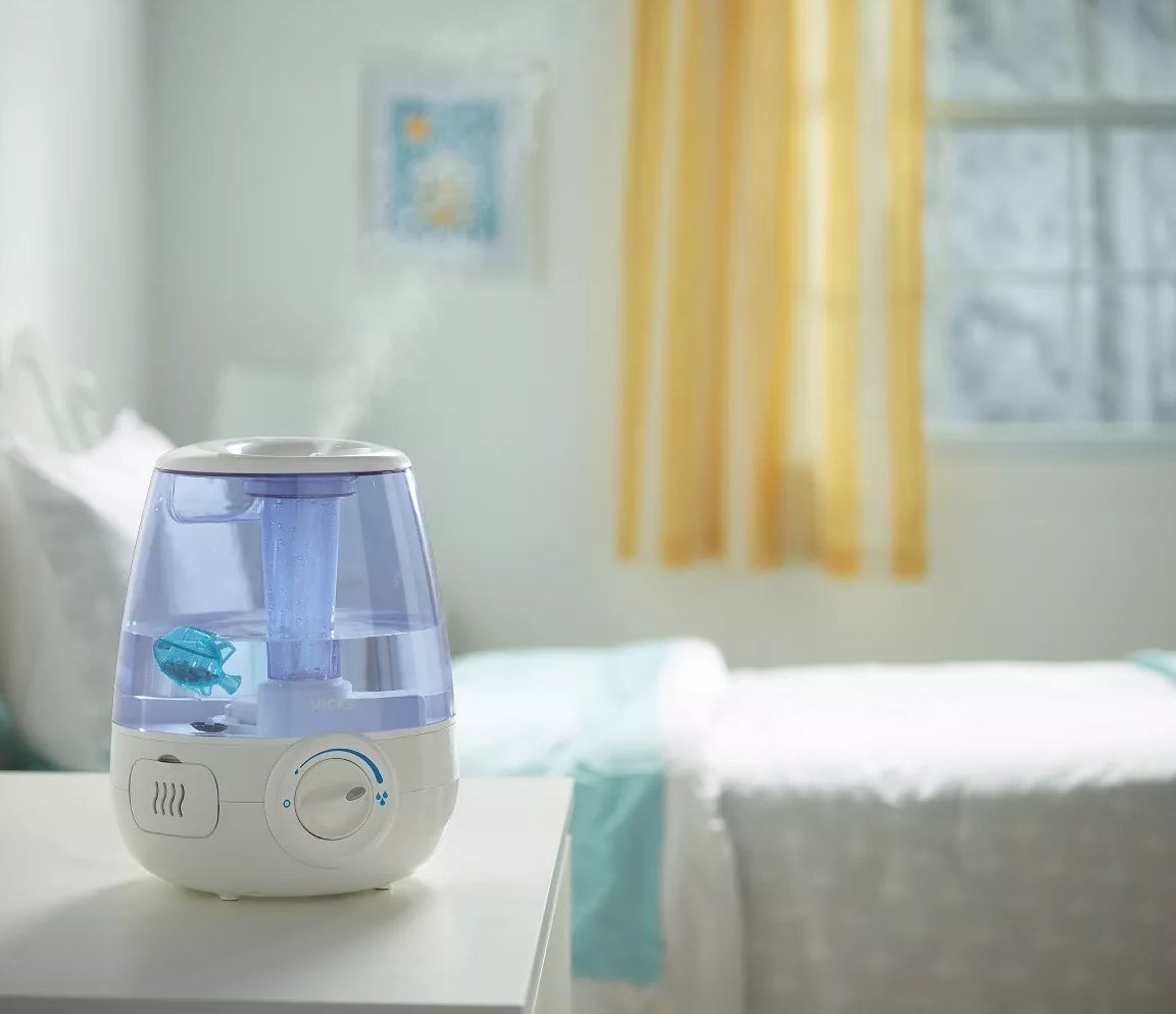 The humidifier sitting on a bedside table, producing steam