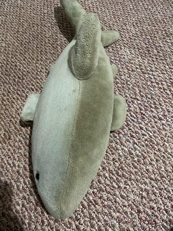 A reviewer's photo of a stuffed shark toy which is half dirty and half clean after using the carpet cleaner