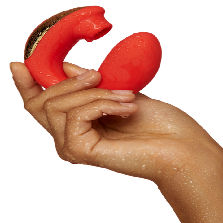 A hand holding the small curved red and gold toy with a suction head and insertable end