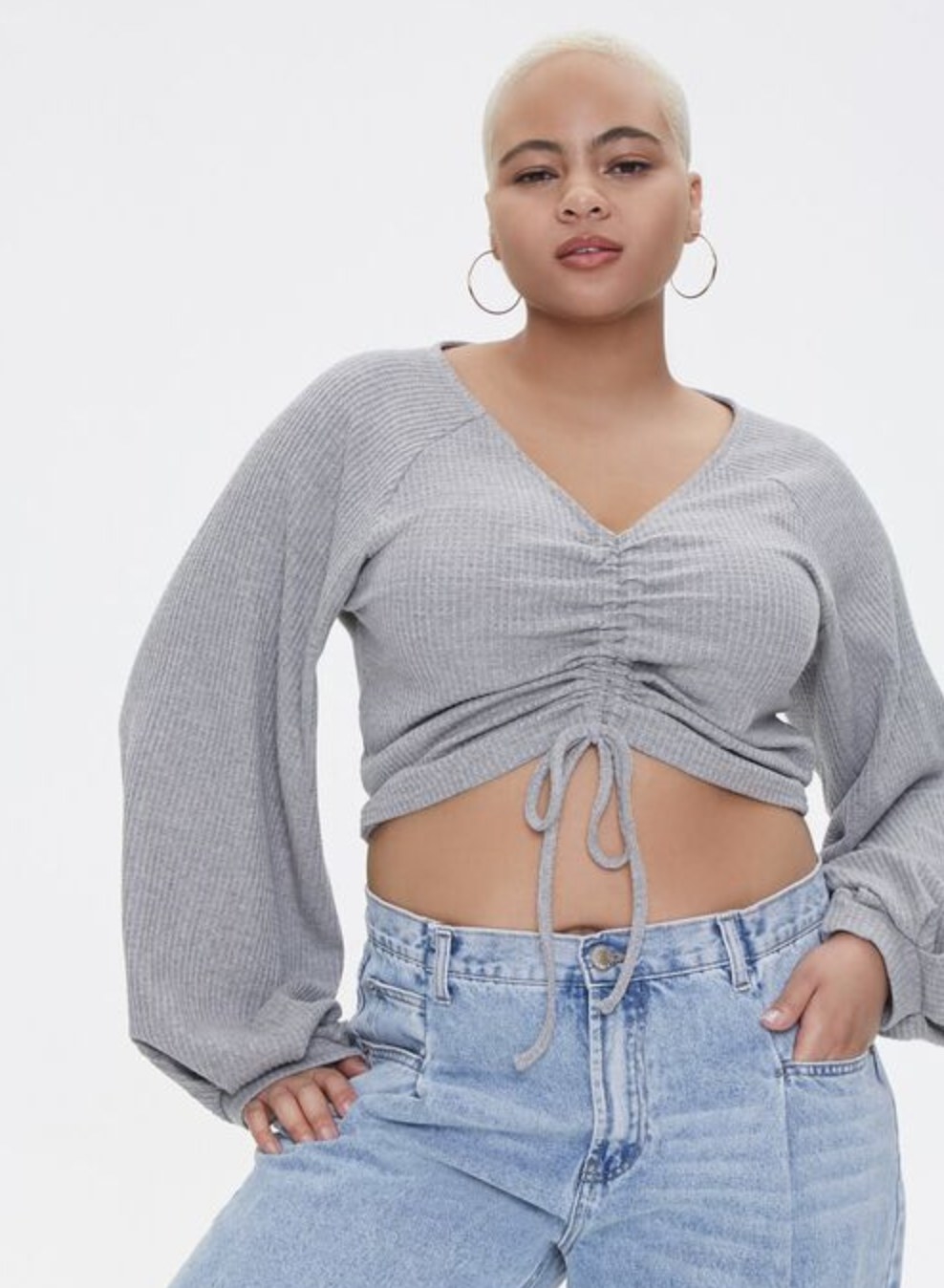 Model is wearing a grey crop top and blue jeans