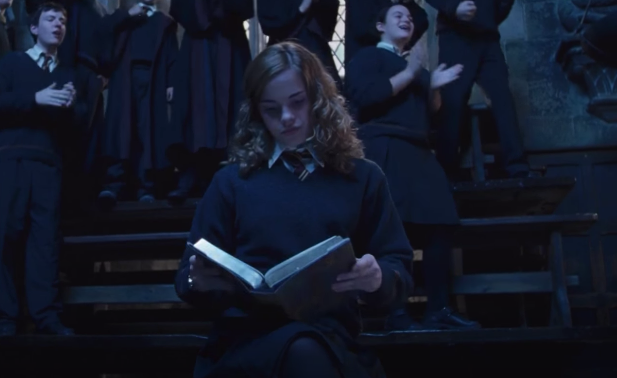 Hermione in &quot;Harry Potter&quot; reading a book while a crowd cheers around her