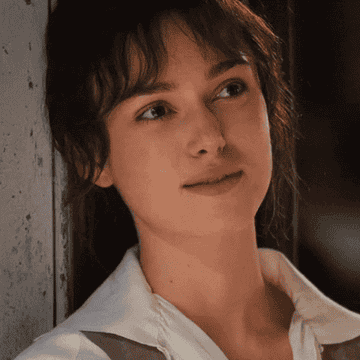 Keira Knightley smiling softly and leaning against door