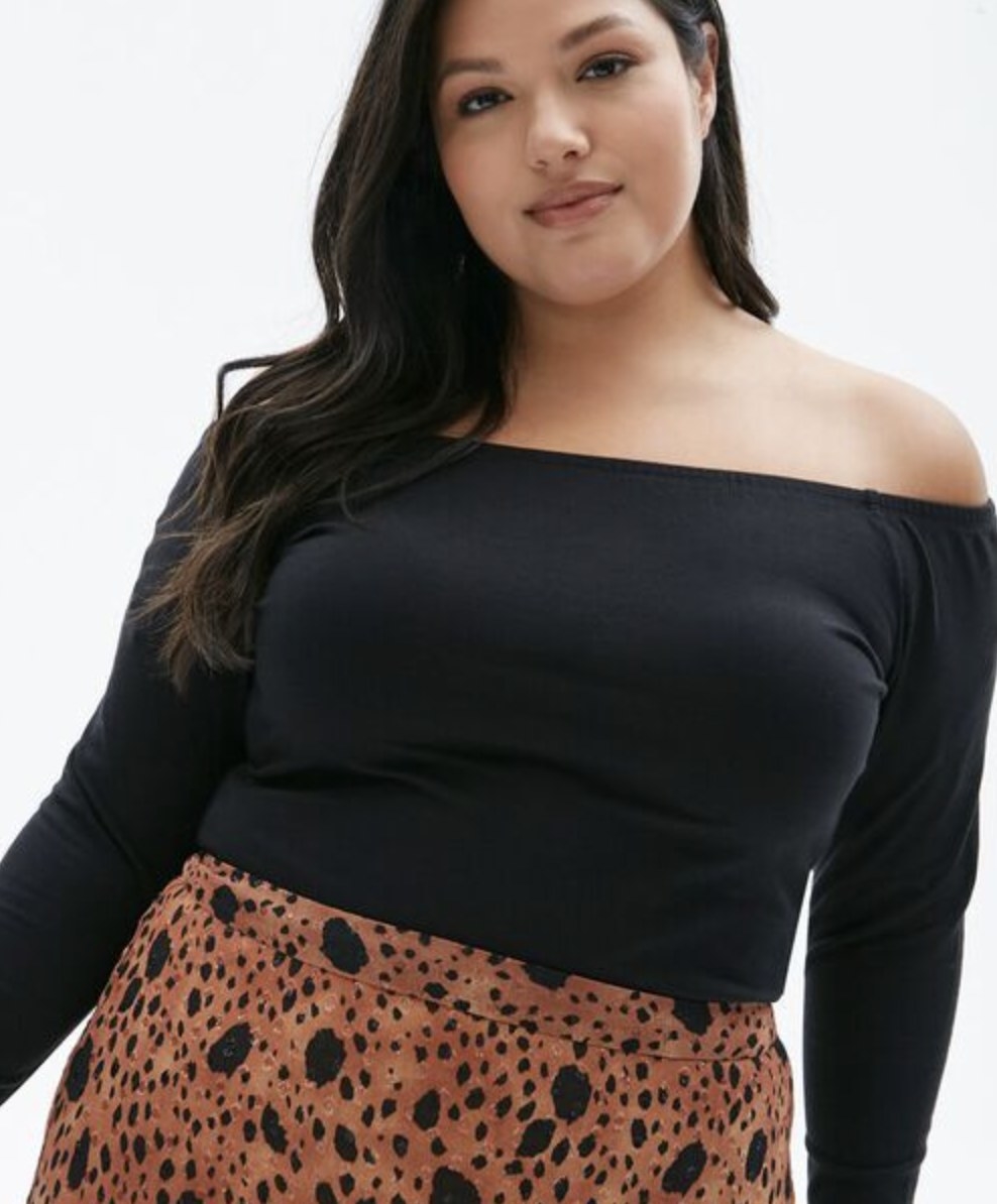 Model is wearing a black off the shoulder top and printed skirt