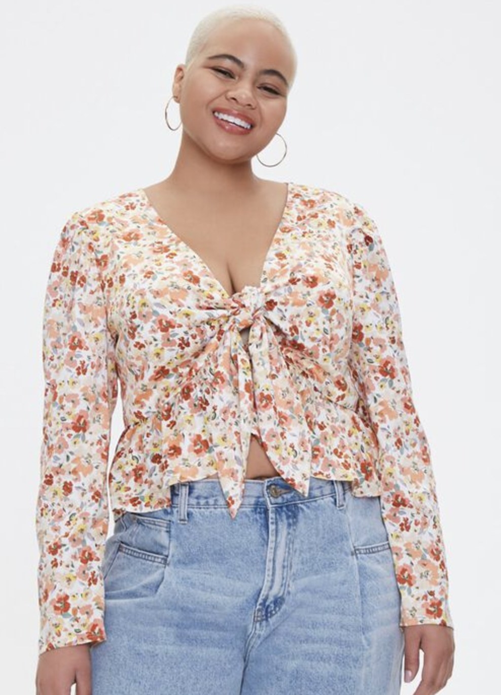 Model is wearing a white and peach floral top and blue jeans