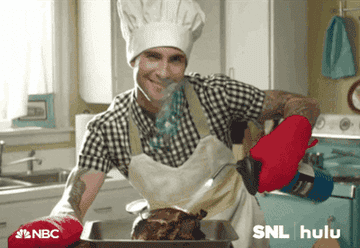 adam levine smiling at the camera after cooking a whole chicken