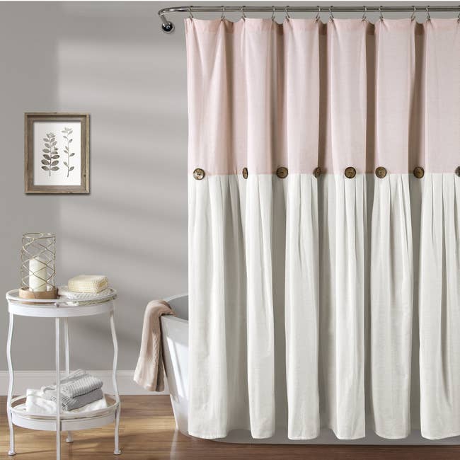 The linen curtain, in pink and white, which has button flourishes across the center