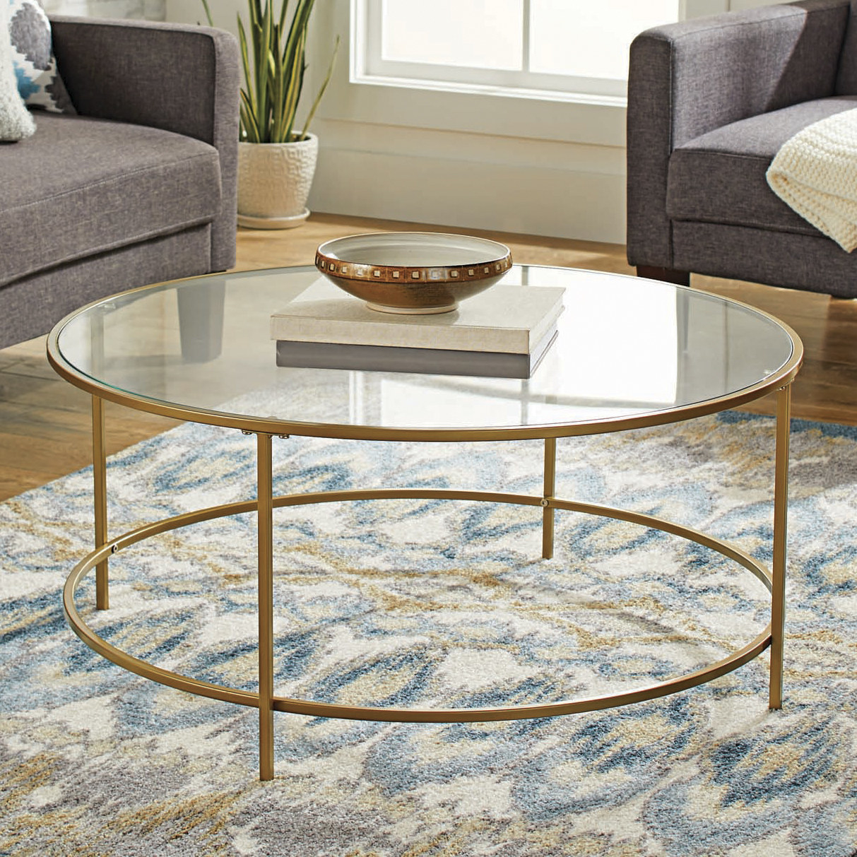 The table, which is circular, with a round, metal frame, four legs, and a circle of safety glass as the top