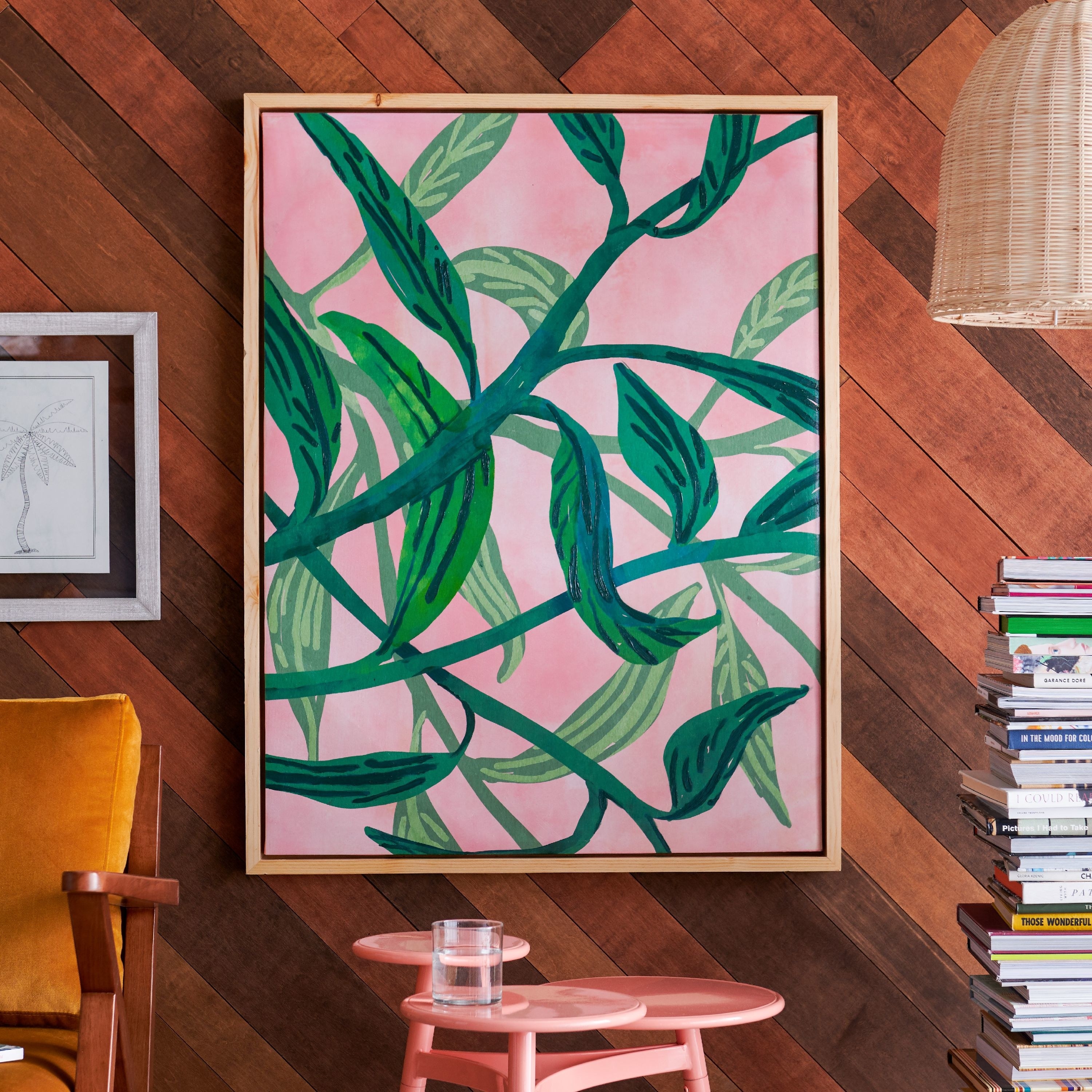 The wall art, which has a pink background and a green drawing of plant vines