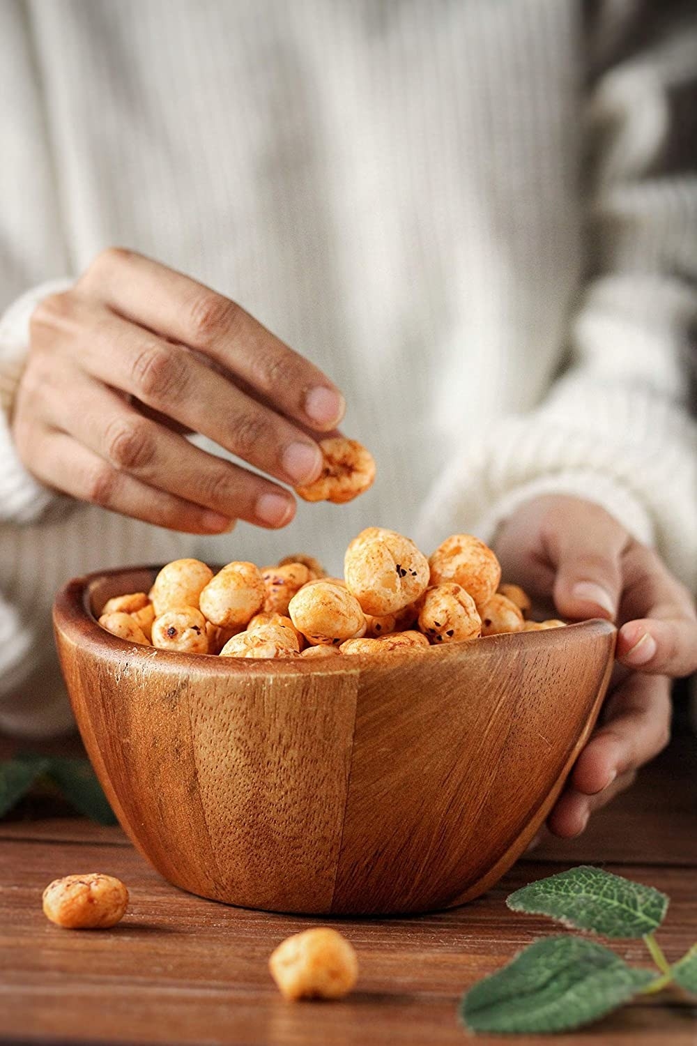 A bowl of peri-peri makhanas with a hand reaching into it 
