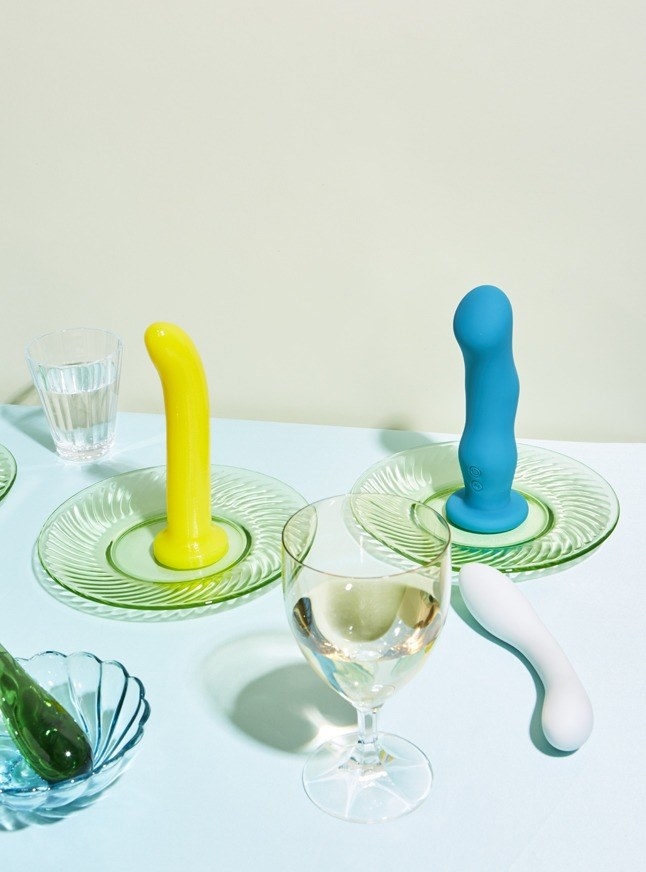 two dildos and a vibrator on a table with glassware