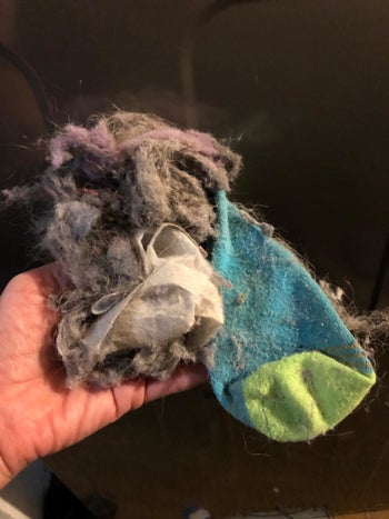 A reviewer holding a sock and clump of lint they cleaned out of their dryer