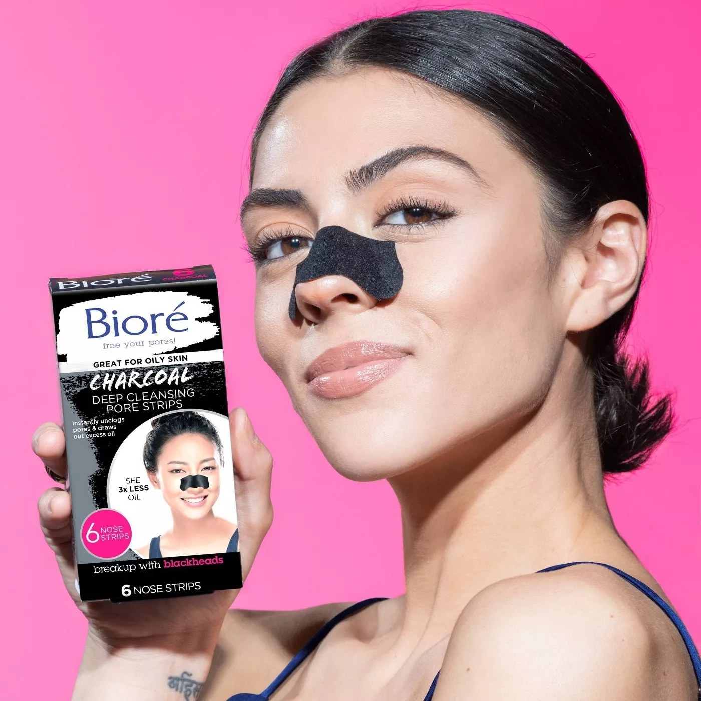A model using a strip on their nose and holding the package of Biore charcoal deep cleansing pore strips 