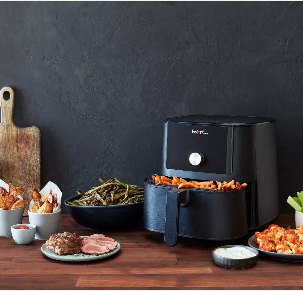The air fryer filled with French fries, displayed among plates of food