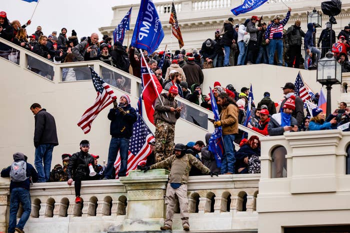 Rioters on the steps of the U.S. Capitol waving U.S. and Trump flags