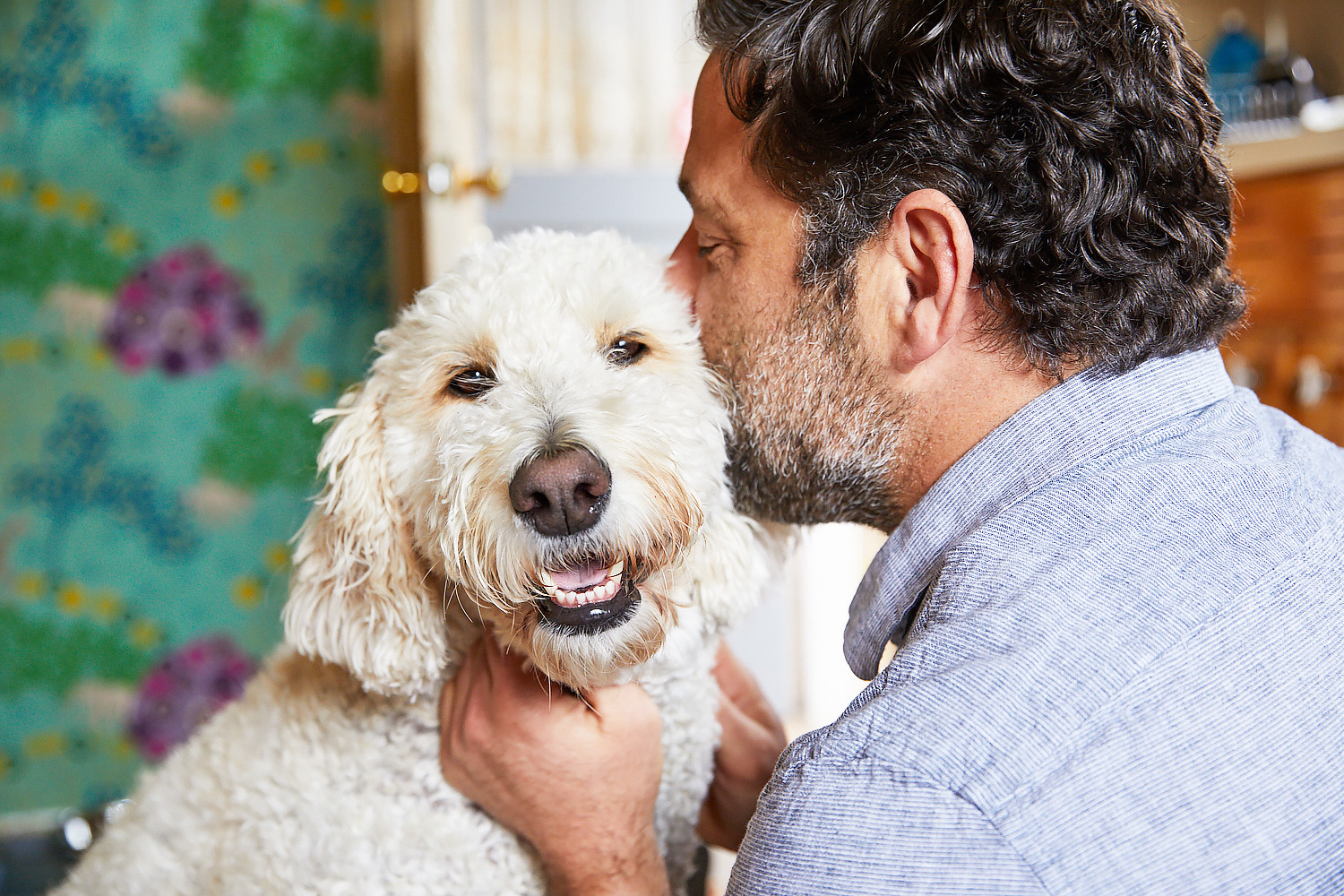 A man kissing his dog on the ear