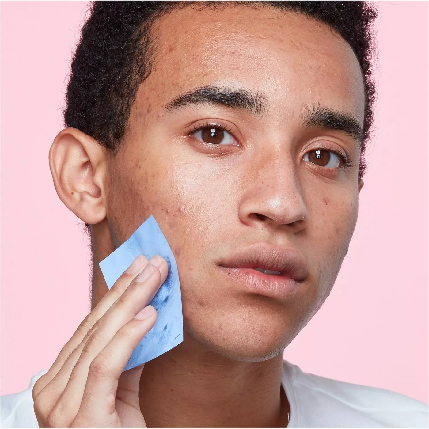 A model using a blotting sheet on their face