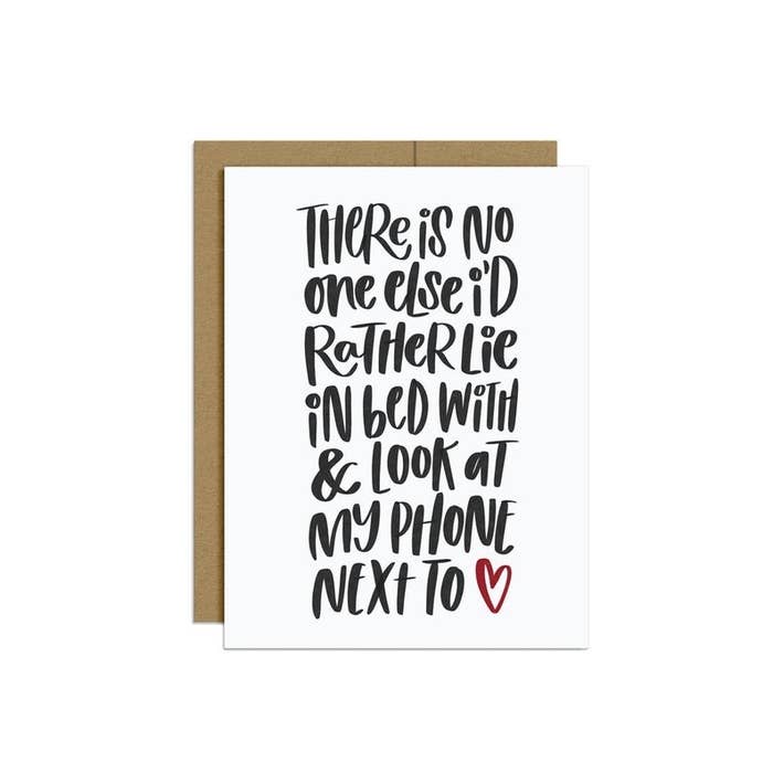 A white card with "There is no one else I'd rather lie n bed with and look at my phone next to" written in black handwriting font
