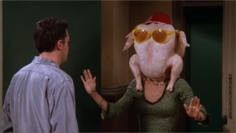 Monica stands in the doorway of Chandler&#x27;s apartment with a turkey with sunglasses and a hat on her head.