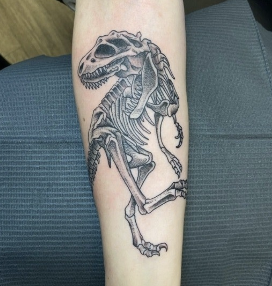 An arm tattoo of a T-Rex&#x27;s bones