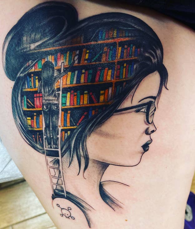 A back tattoo of a woman&#x27;s head and a colorful bookshelf over her hair