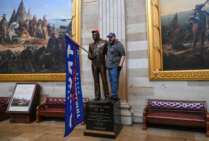A rioter posing next to a statue of Gerald R Ford in the Capitol