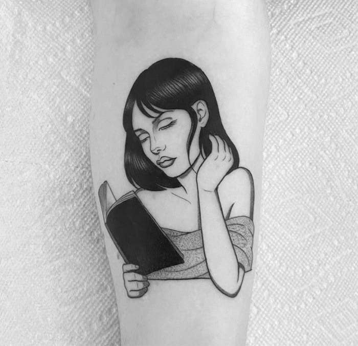 A tattoo of a woman reading a book
