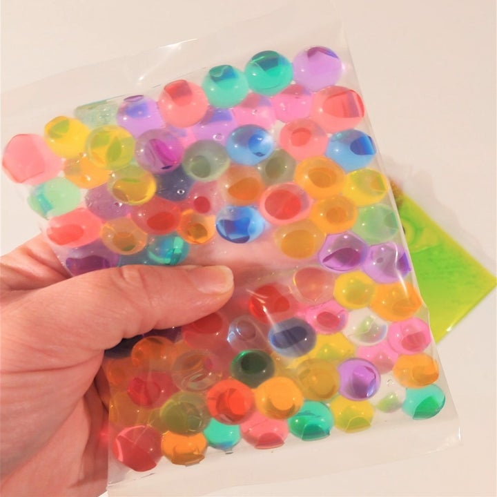 clear rectangle filled with slimey-looking rainbow balls 
