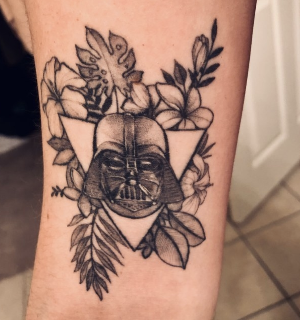 An arm tattoo with Darth Vader&#x27;s helmet surrounded by flowers