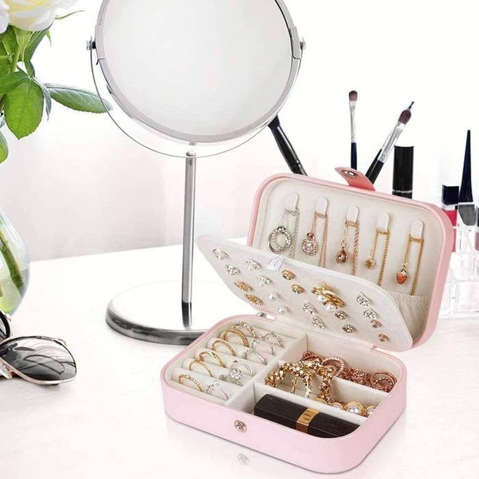 jewelry box filled with necklaces, rings, a lipstick, earrings, and bracelets