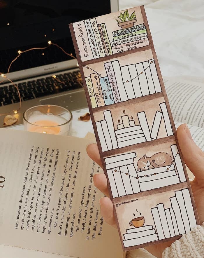 a person holding the bookmark with blank books on painted shelves 