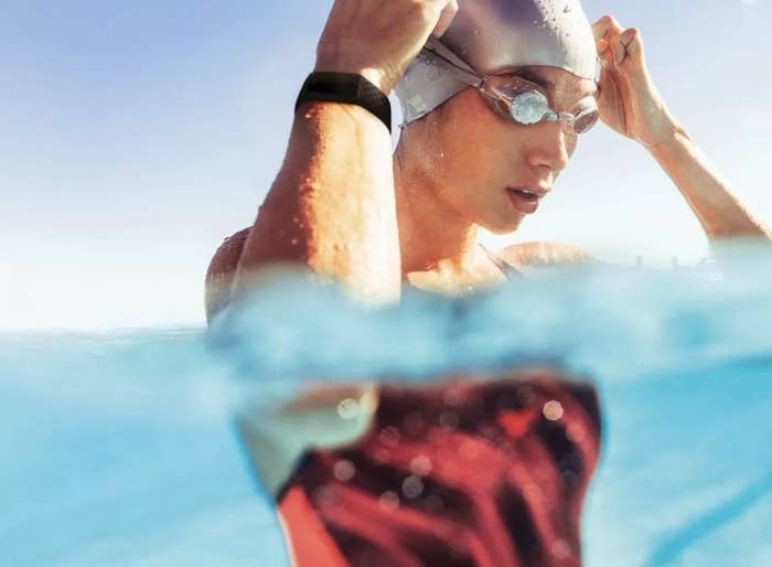 Swimmer is in water wearing a Fitbit