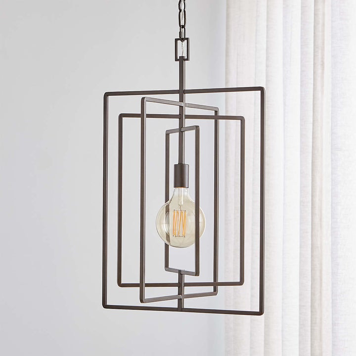 a pendant light with metal rectangular framing around a hanging bulb