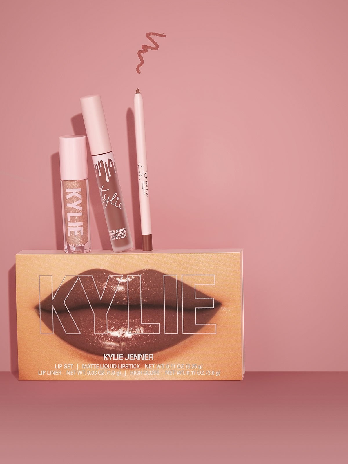 a lip glass, a lipstick, and a lip liner on top of packaging with kylie&#x27;s lips on it