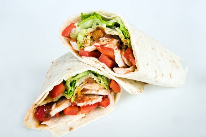 A tortilla wrap filled with lettuce, tomato, and a protein